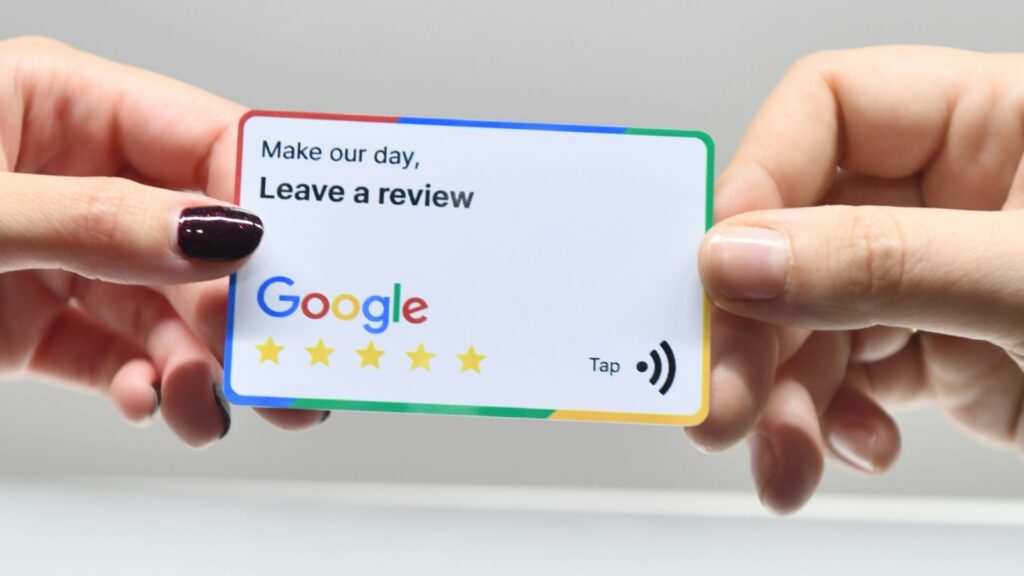 Business owner using smartphone with NFC review card to automate Google review requests, modern blue tech background.